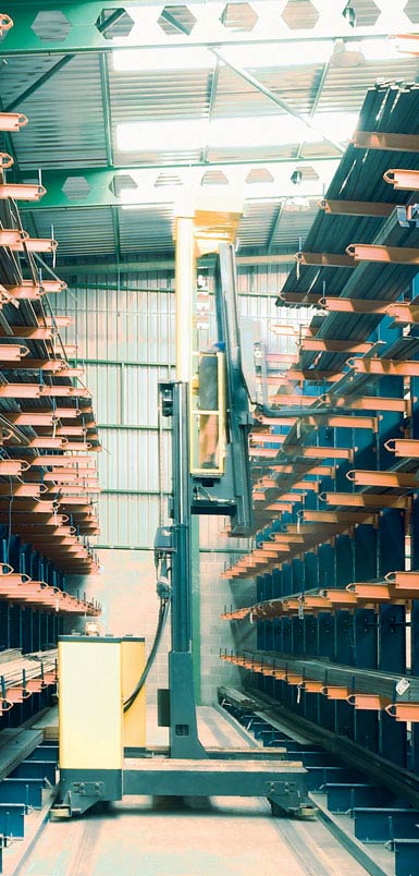 Imagen de un montacargas retráctil de carga lateral en una bodega de perfiles metálicos. 